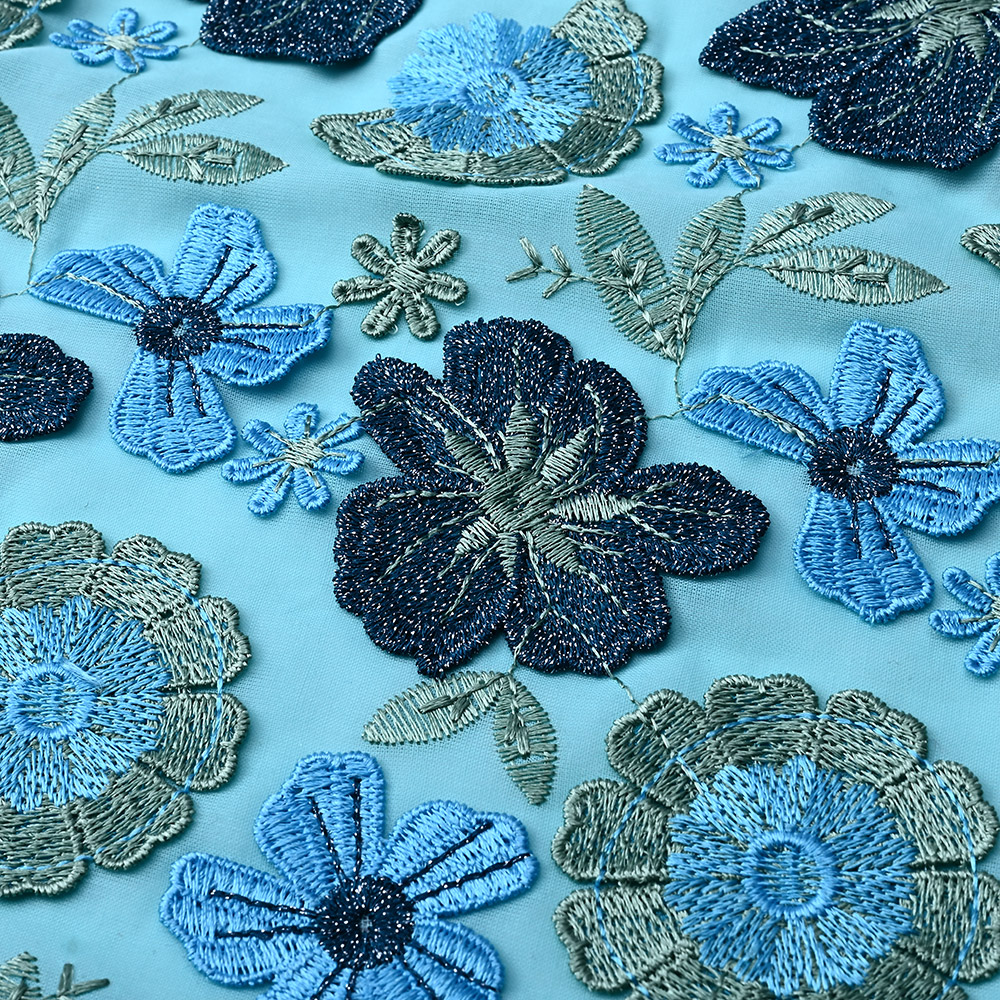 Navy and sky blue 3D flowers on aqua blue lace fabric close-up