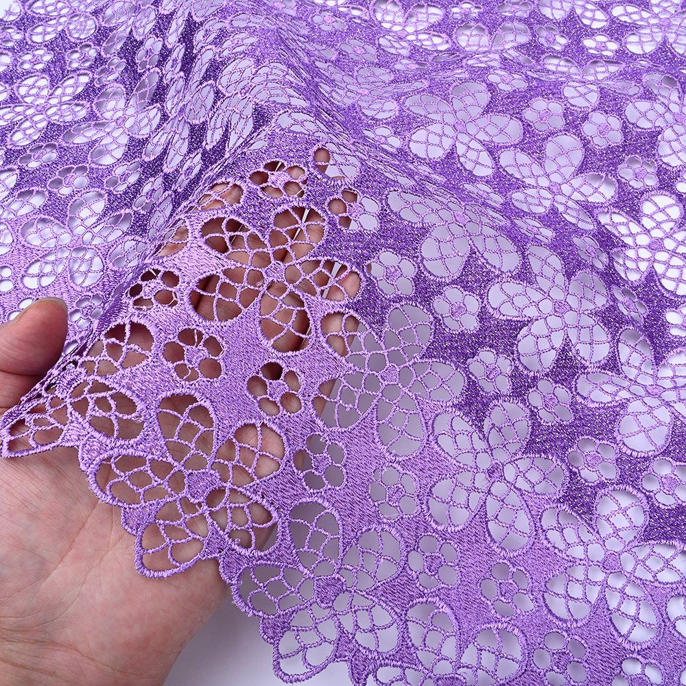 Open floral cutwork of lavender guipure lace fabric in hand