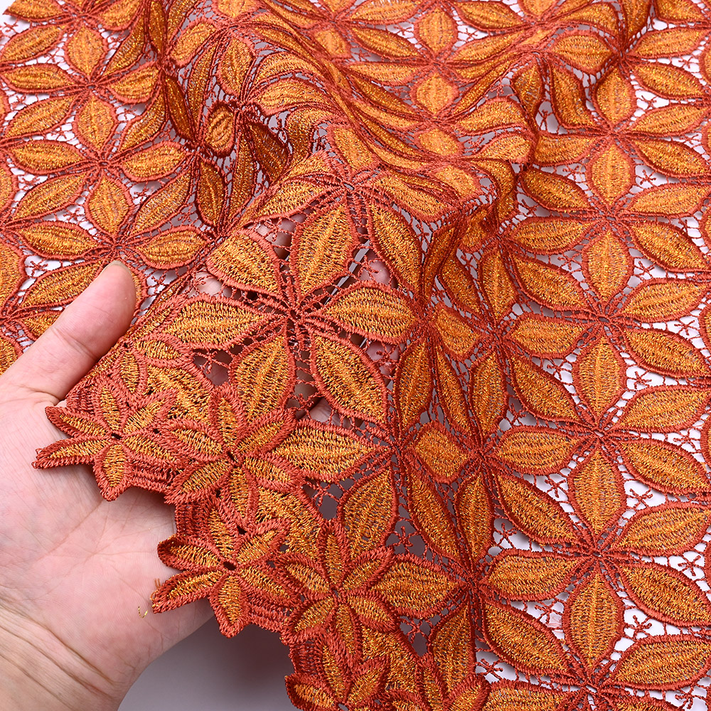 Two-tone burnt orange star flowers on 3D guipure lace in hand